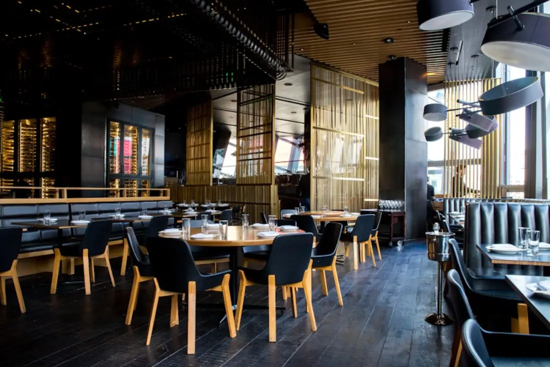 A warmly lit restaurant dining room with wooden tables