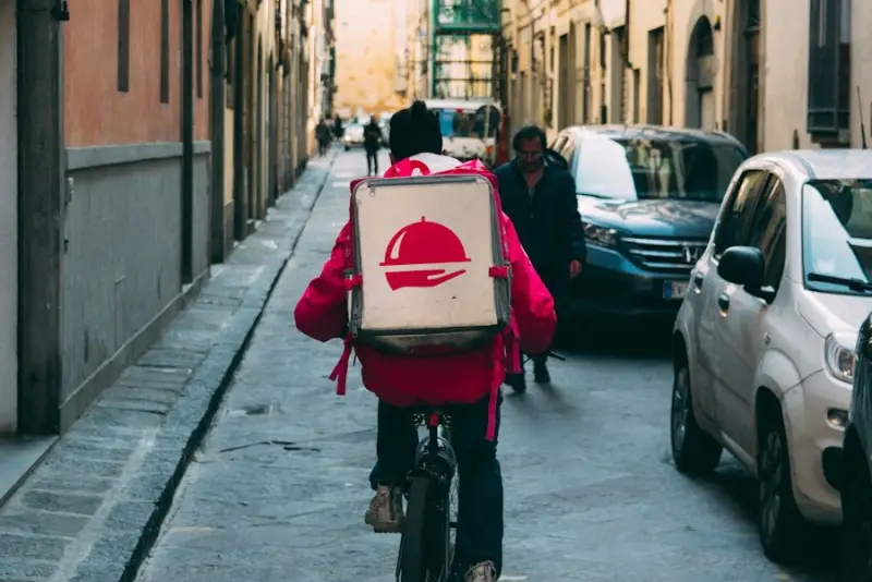 A delivery rider cycling through a city lane